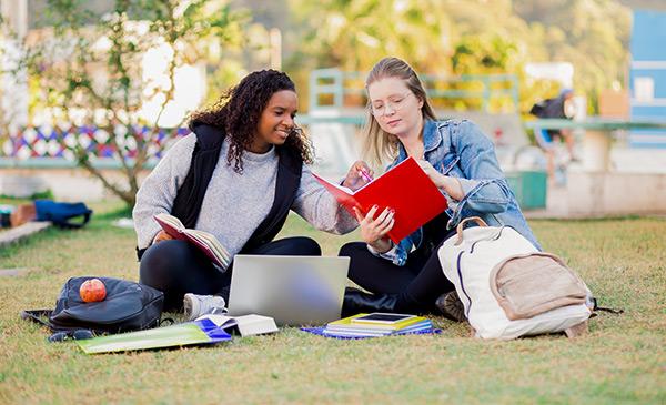 two female college students sitting on a lawn